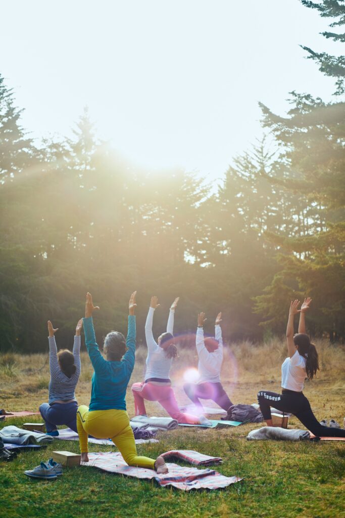 A group of people outside in a field doing yoga